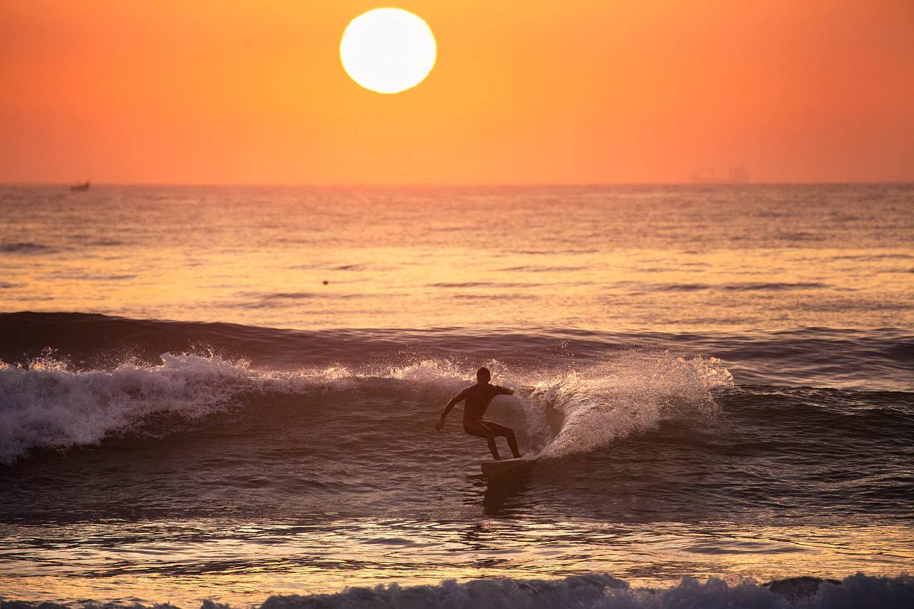 Surfer carving a sunset wave at Banana Beach in Aourir