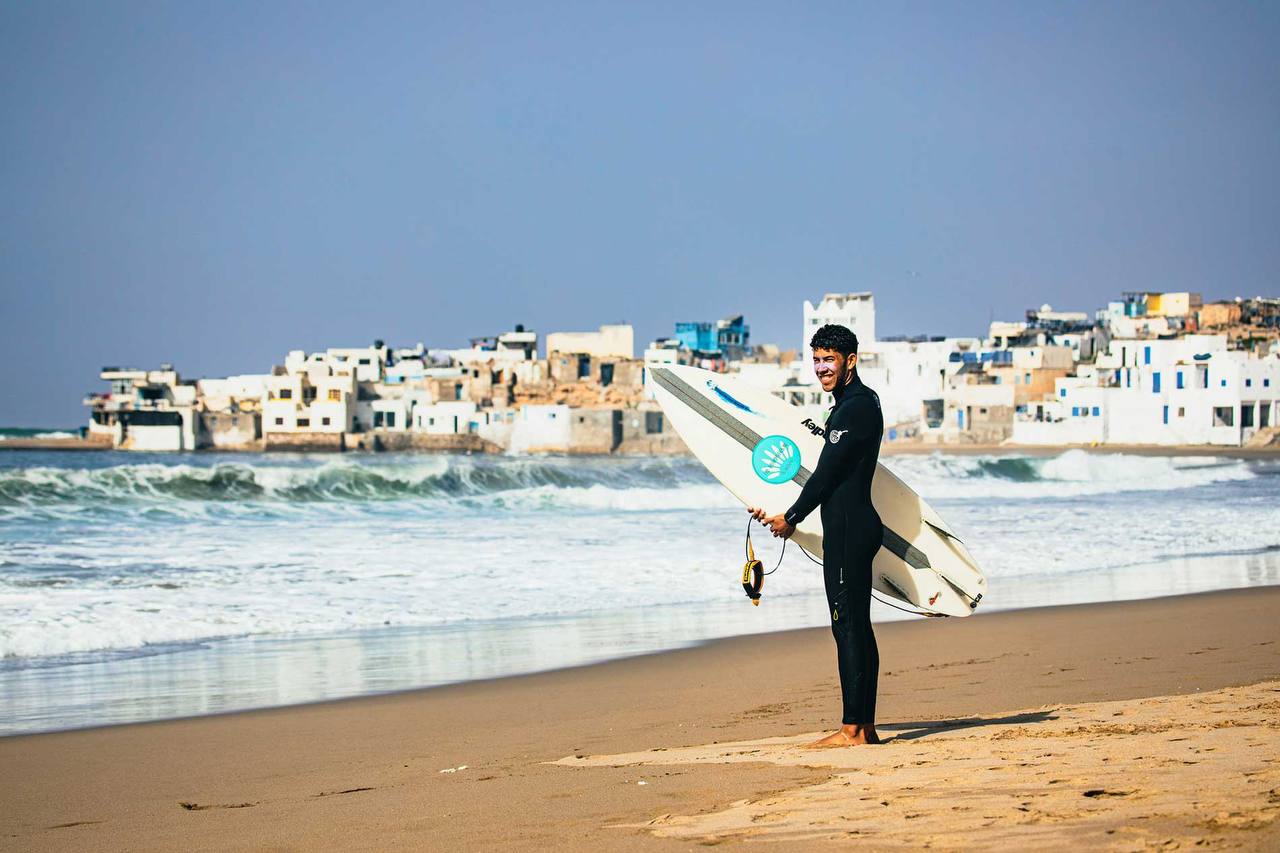 Surfeur sur la plage avec la côte de Taghazout en arrière-plan